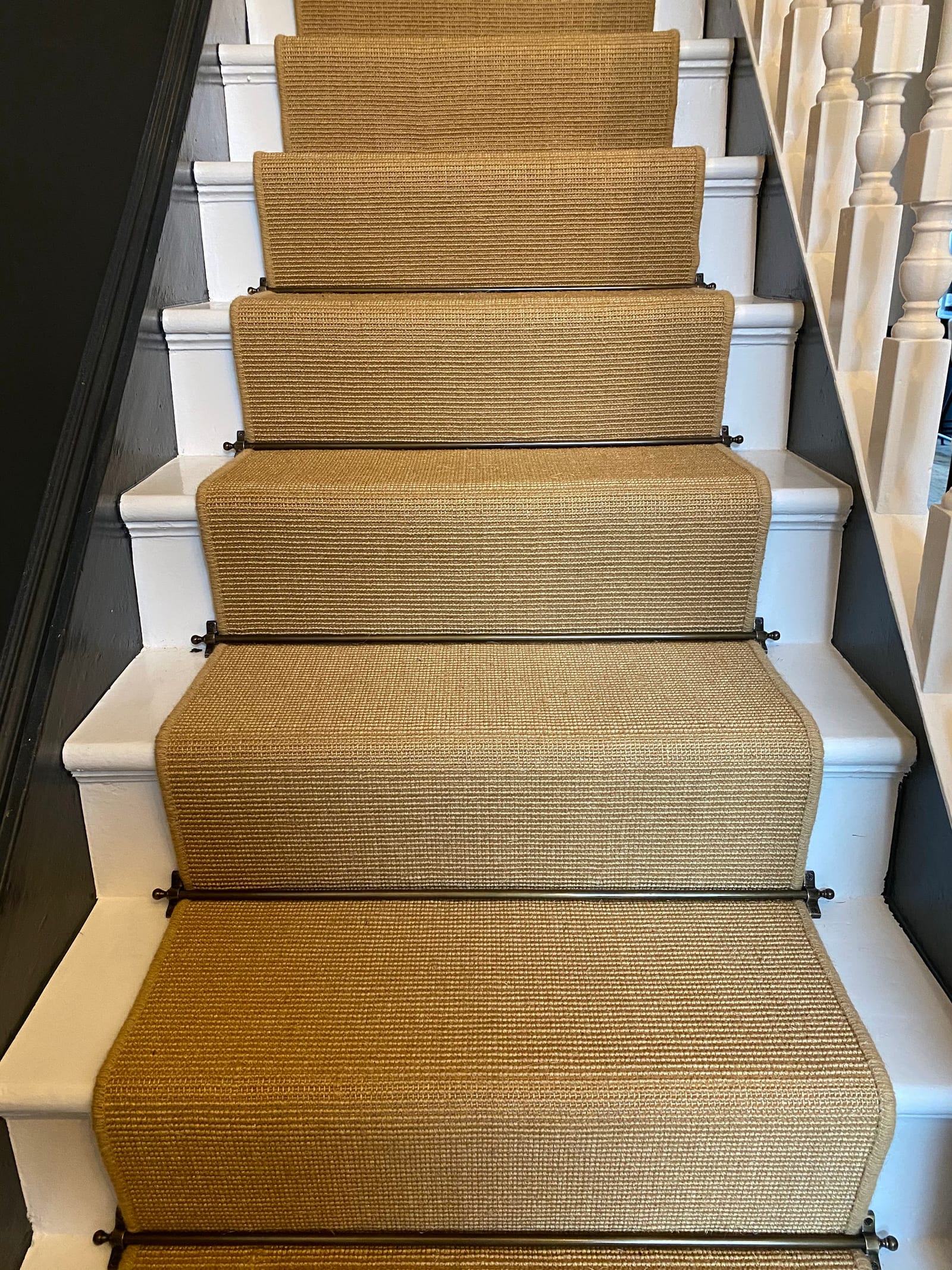 Neutral fitted runner following a staircase with white painted spindles