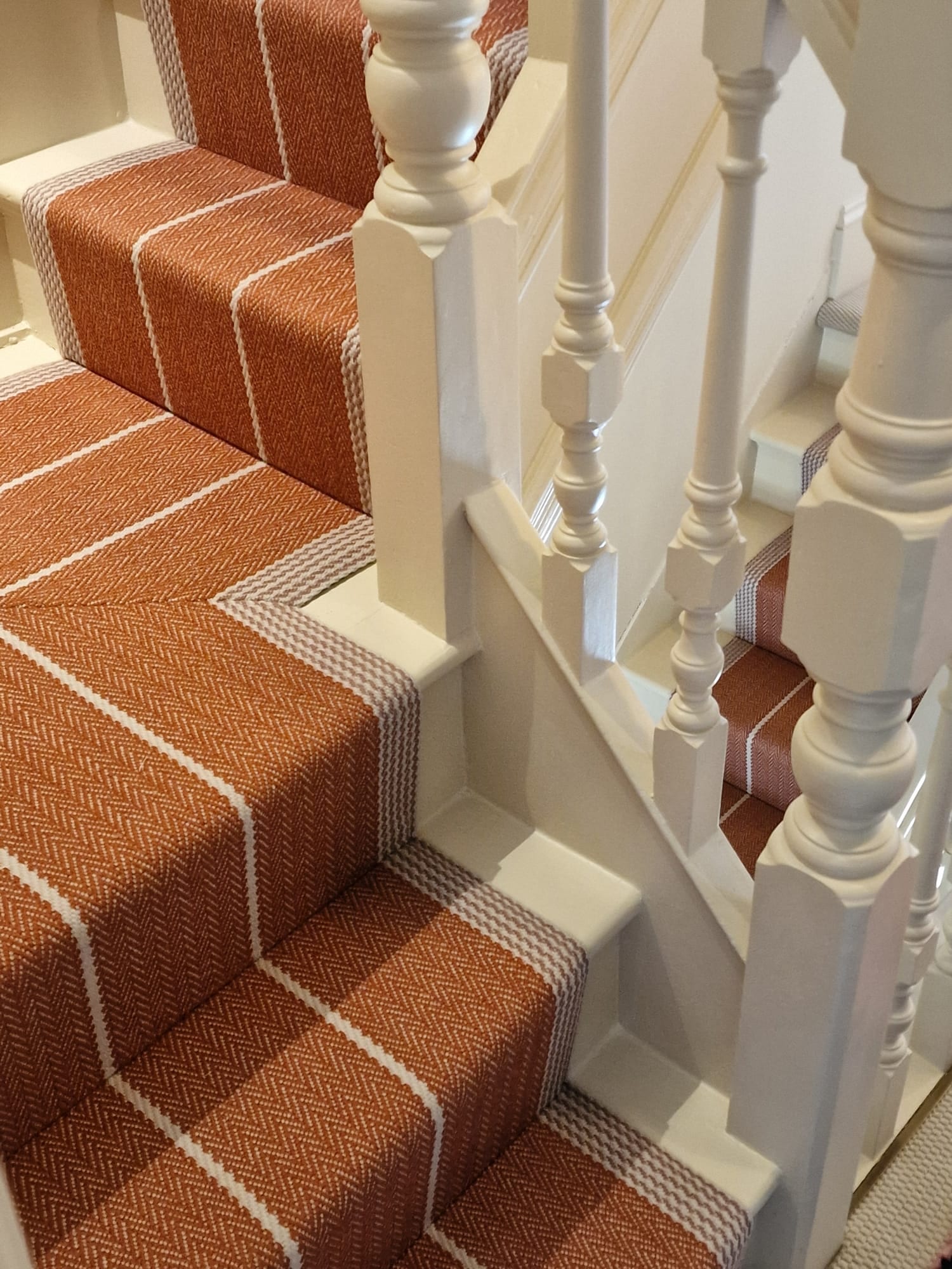 Rust and ivory patterned runner neatly fitted around a staircase turn
